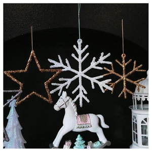 Close-up of sparkling gold star and white snowflake ornaments with festive scene