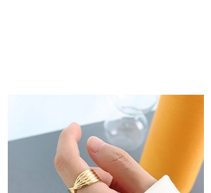 Nahaufnahme eines mehrlagigen goldenen Wellenrings am Finger im modernen, schlichten Design