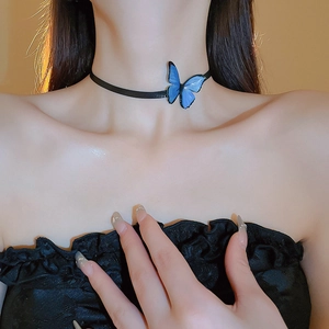 Close-up of a black choker necklace with a blue butterfly pendant on a model