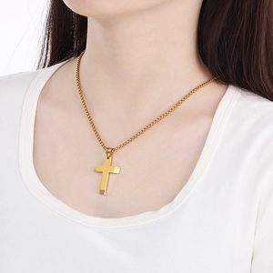 Polished gold cross pendant necklace on a box chain worn by a male model