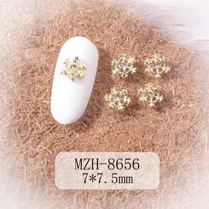 Detailed close-up of 7x7.5mm gold snowflake nail art charms with crystal center