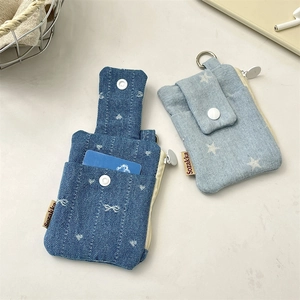 Detail of denim card holder with white button and zipper closure in blue tones