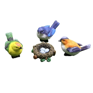 Vibrant resin bird figurines with detailed feathers and a small nest with three eggs
