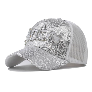 Détail d'une casquette argentée à paillettes avec lettrage Baby en strass étincelants