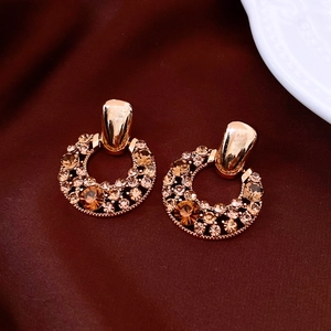 Dettaglio macro di orecchini vintage placcati in oro con zirconi su tessuto bordeaux