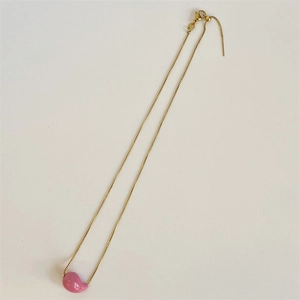 Detailed shot of golden box chain with a pink bean pendant and lobster clasp closure