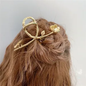 Dettaglio della molletta per capelli a rosa dorata vintage su uno chignon elegante
