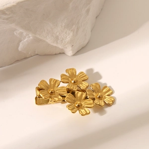 Détail de quatre barrettes fleurs dorées aux pétales texturés et pince crocodile en métal