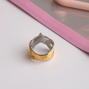 Gros plan sur une bague large en acier titane avec bords dorés et centre argenté rainuré