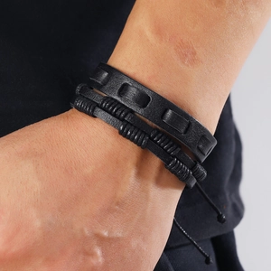 Close-up of a 5-piece set of black braided leather bracelets with tree of life on a wrist