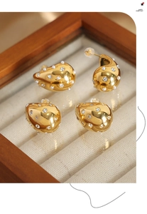 Macro view of gold teardrop earrings with embedded pearls and rhinestones on velvet
