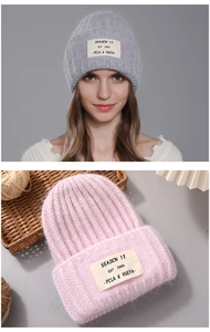 Detail of warm winter beanies in gray and pink with vintage patch lettering design
