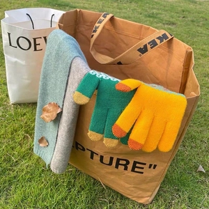 Winter set with green and yellow knit gloves and matching scarf on a shopping bag
