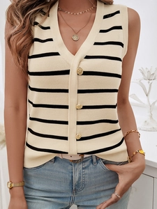 Dettaglio del gilet in maglia beige a righe nere con eleganti bottoni dorati