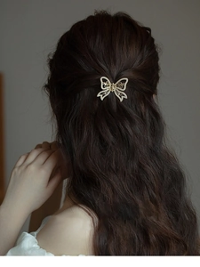Macro detail of a golden butterfly hair claw clip with pearls on long wavy hair