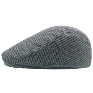 Detailed close-up of houndstooth wool tweed pattern on a grey winter newsboy cap