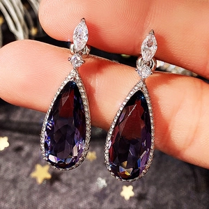 Gros plan de boucles d'oreilles pendantes avec zircons violets et détails pavés