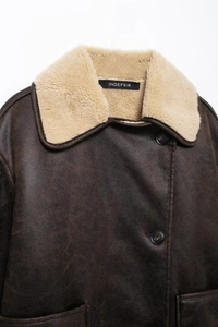 Detail of dark brown faux shearling jacket with cream lamb wool collar and vintage texture