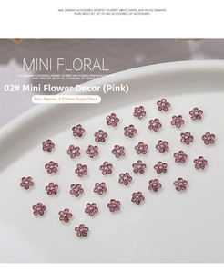 Detail shot of mini pink 3D flower nail charms with white crystal center on white tray