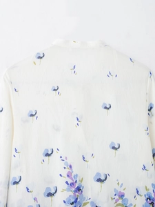 Detailed view of white floral shirt fabric with delicate blue and purple flower patterns