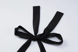 Détail d'une ceinture en tissu noir nouée en nœud papillon sur une robe léopard