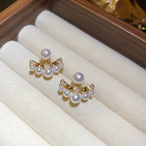 Elegant gold pearl stud earrings with zircon stones on a soft cream jewelry box display