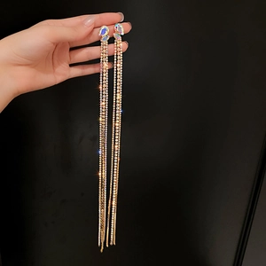 Macro shot of long golden tassel earrings with iridescent blue and purple rhinestones