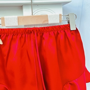 Red satin pajamas shorts with elastic waistband and drawstring detail on hanger