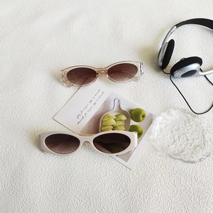 Flat lay of vintage oval sunglasses in tea brown and cream with aesthetic props