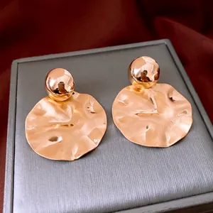 Minimalist rose gold round stud earrings with hammered texture on velvet jewelry box