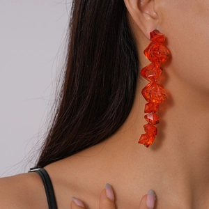 Close-up of orange irregular geometric acrylic drop earrings on a model's ear