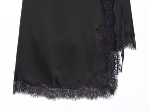 Detailed close-up of the black satin skirt hem featuring delicate floral lace trim