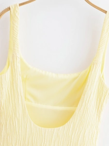 Detail of pale yellow sleeveless dress featuring unique wrinkled texture on the neckline