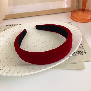 Detail view of a wide burgundy velvet headband with anti-slip texture on a vintage tray