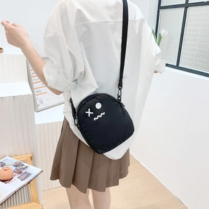 Détail d'un sac bandoulière en toile noire avec visage de dessin animé mignon
