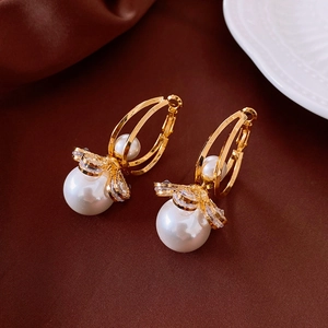 Detailed view of elegant gold pearl earrings with sparkling crystals on silk background