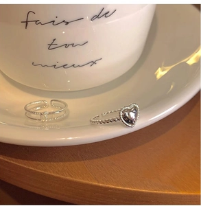 Close-up of silver heart-shaped and double-layered open rings on a white porcelain dish
