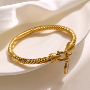 Detailed close-up of a 18k gold-plated twisted rope bracelet with Roman numeral disc charm
