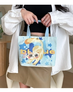 Detailed close-up of a blue canvas tote featuring a cute cartoon cat print and sturdy handles