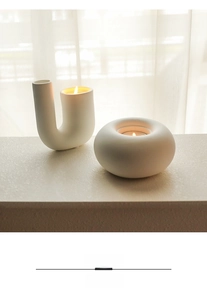 Macro detail of white matte ceramic candle holders in geometric U-shape and round minimalist style