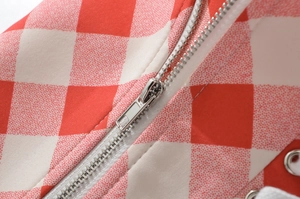 Macro shot of red plaid fabric featuring silver metal zipper and eyelet detailing