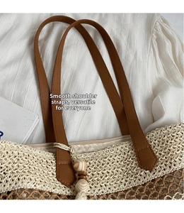 Detail of woven straw beach bag featuring brown leather straps and beaded tassels