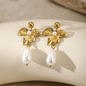 Detailed close-up of golden floral earrings featuring elegant white teardrop pearls