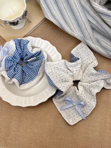 Detail of blue plaid lace scrunchie and bow hair tie set with pearl accents on a plate