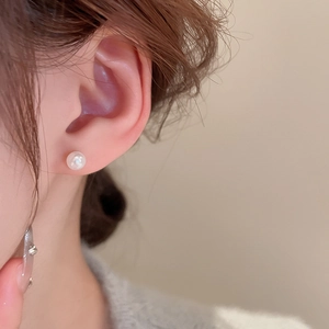 Close-up of elegant white pearl stud earring worn on model for a minimalist style