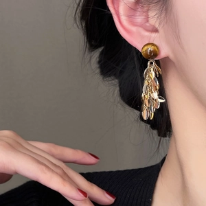 Detail view of retro tassel earrings with tiger eye stone and golden sequins on a model