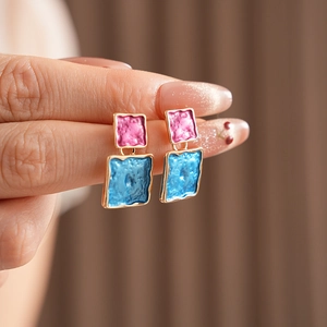 Detail of square geometric earrings with pink and blue enamel and gold-plated hammer texture