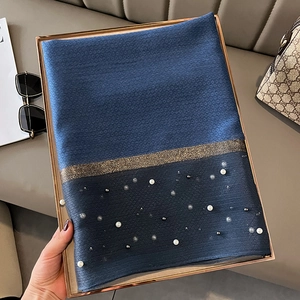 Close-up of navy silk-like scarf with gold shimmer band and elegant pearl beadwork details