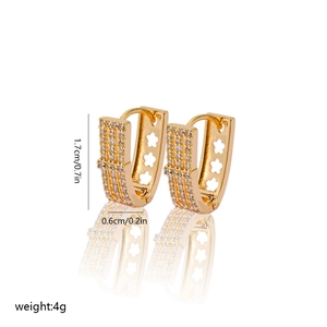 Macro view of gold V-shape earrings with inlaid zircons and floral cutouts on white base