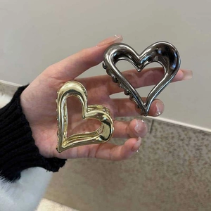 Detail of hollow heart-shaped metal hair claws in glossy gold and gunmetal finishes